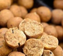 Close-up of several round, beige-colored kachoris with a crunchy texture, with a few cut open to reveal their crumbly, spiced filling. The background shows an assortment of whole kachoris, akin to bait up in pressured waters, emphasizing the detailed texture and color of the snack.